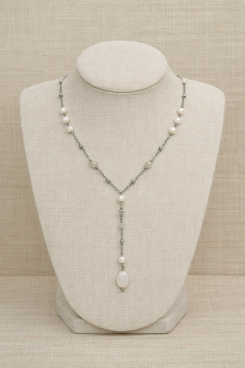 Necklace with pearls and stones on a mannequin bust against a beige background