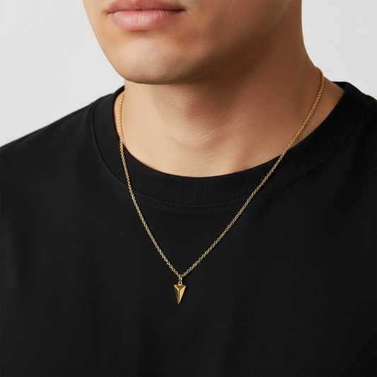 Gold necklace with a pyramid pendant worn by a male person against a neutral background