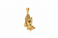 A polished yellow gold pendant shaped like praying hands, shown against a plain white background.