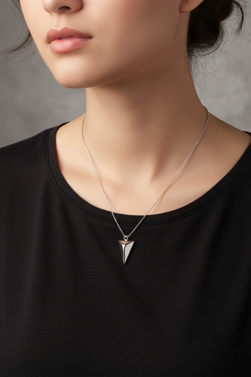 Necklace with a pyramid pendant worn by a women against a neutral background