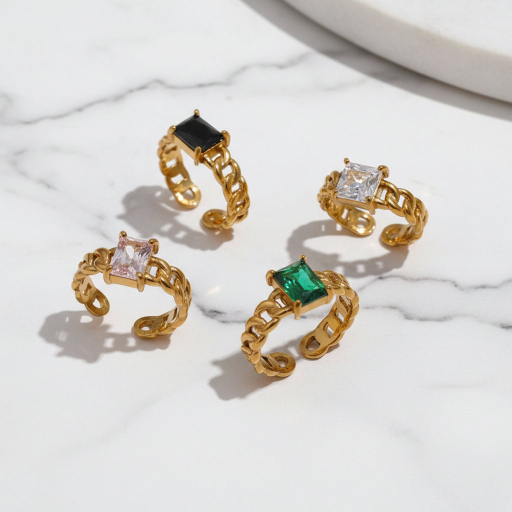 A collection of Adele CZ Chain Rings in gold plating with varying colorful gemstones in a chain design.