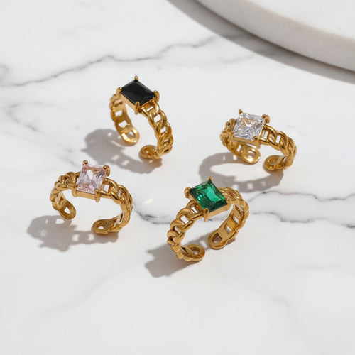 A collection of Adele CZ Chain Rings in gold plating with varying colorful gemstones in a chain design.